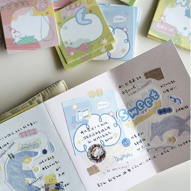 Open notebook with decorative stickers and cartoon illustrations on a light surface